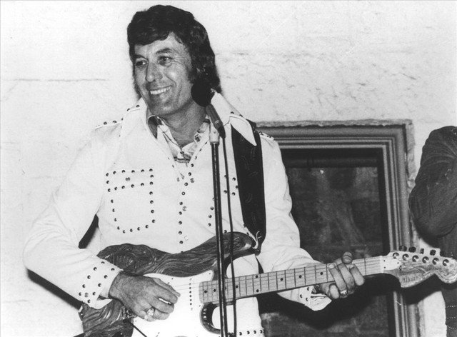 Fotografía de Carl Perkins con guitarra, ícono del estilo rockabilly de los años 50 en modapinup.com